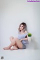 A woman sitting on a white stool next to a plant.