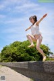 A woman in a white top and yellow sandals jumping in the air.