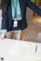 A woman in a blue shirt and skirt standing at a table.