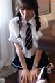 A woman in a school uniform sitting on the floor.