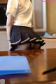 A woman in a school uniform is sitting at a desk.