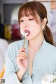 A woman eating a piece of food with a spoon.