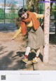 A woman leaning against a pole in a park.