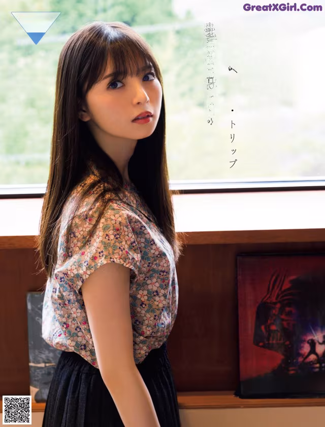 A woman standing in front of a window next to a book shelf.