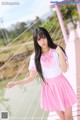 A woman in a pink skirt and white shirt posing on a bridge.