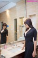 A woman in a black dress standing in front of a mirror.