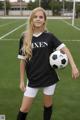 A young woman holding a soccer ball on a field.