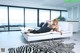 A woman laying on a white couch in a living room.