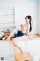 A woman sitting on top of a wooden chair in a kitchen.