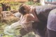 A woman in a white dress sitting on a rock in the water.