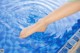 A woman's feet in a swimming pool with water splashing around them.