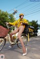 A woman in a yellow raincoat riding a bike.