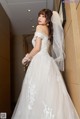 A woman in a wedding dress leaning against a wall.