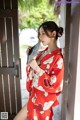 A woman in a red kimono holding a fan.