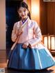 A woman in a blue and pink hanbok is posing for a picture.