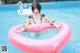 A woman in a bikini sitting on an inflatable ring in a pool.