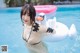 A woman in a bikini standing in a pool with a swan float.