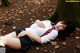 A woman in a school uniform laying on the ground.