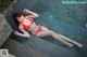 A woman in a red bikini laying on the edge of a pool.