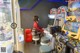 A woman sitting on a stool in front of a video game machine.